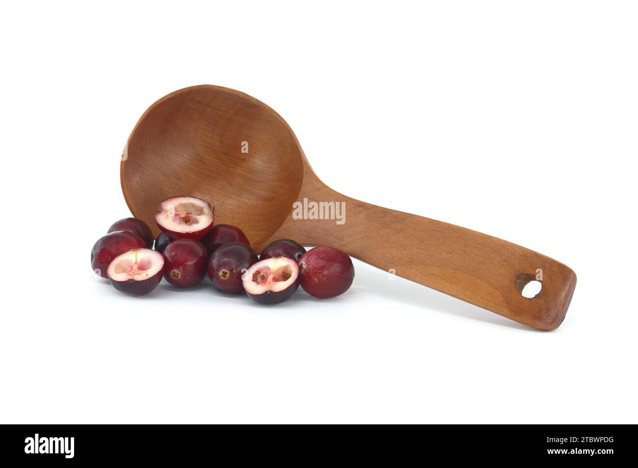 Fresh cranberries and cranberry berry cut in half in front of wooden spoon isolated on white background Stock Photo