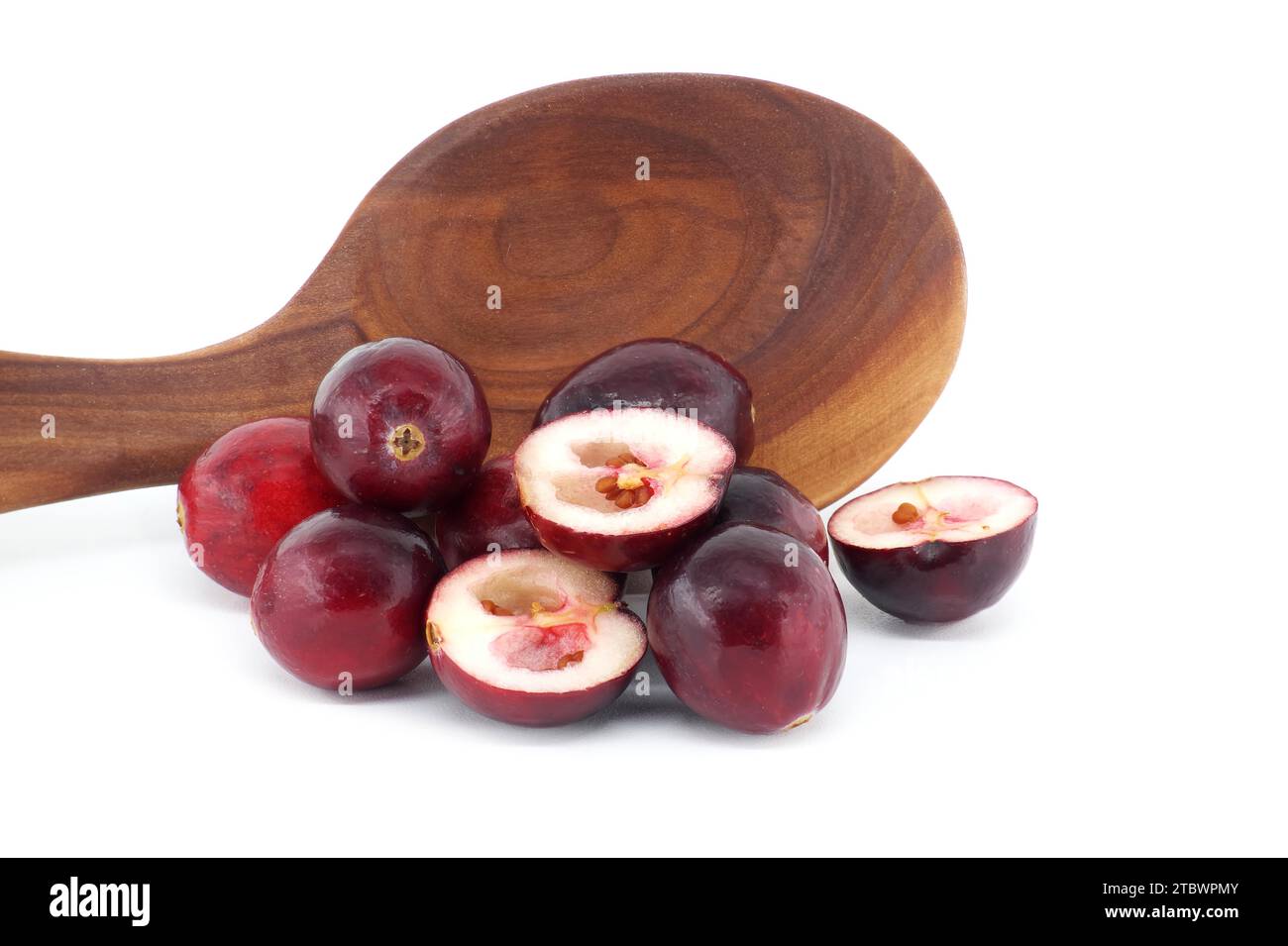 Half cut cranberry berry and fresh cranberries against of wooden spoon isolated on white background, full depth of field Stock Photo