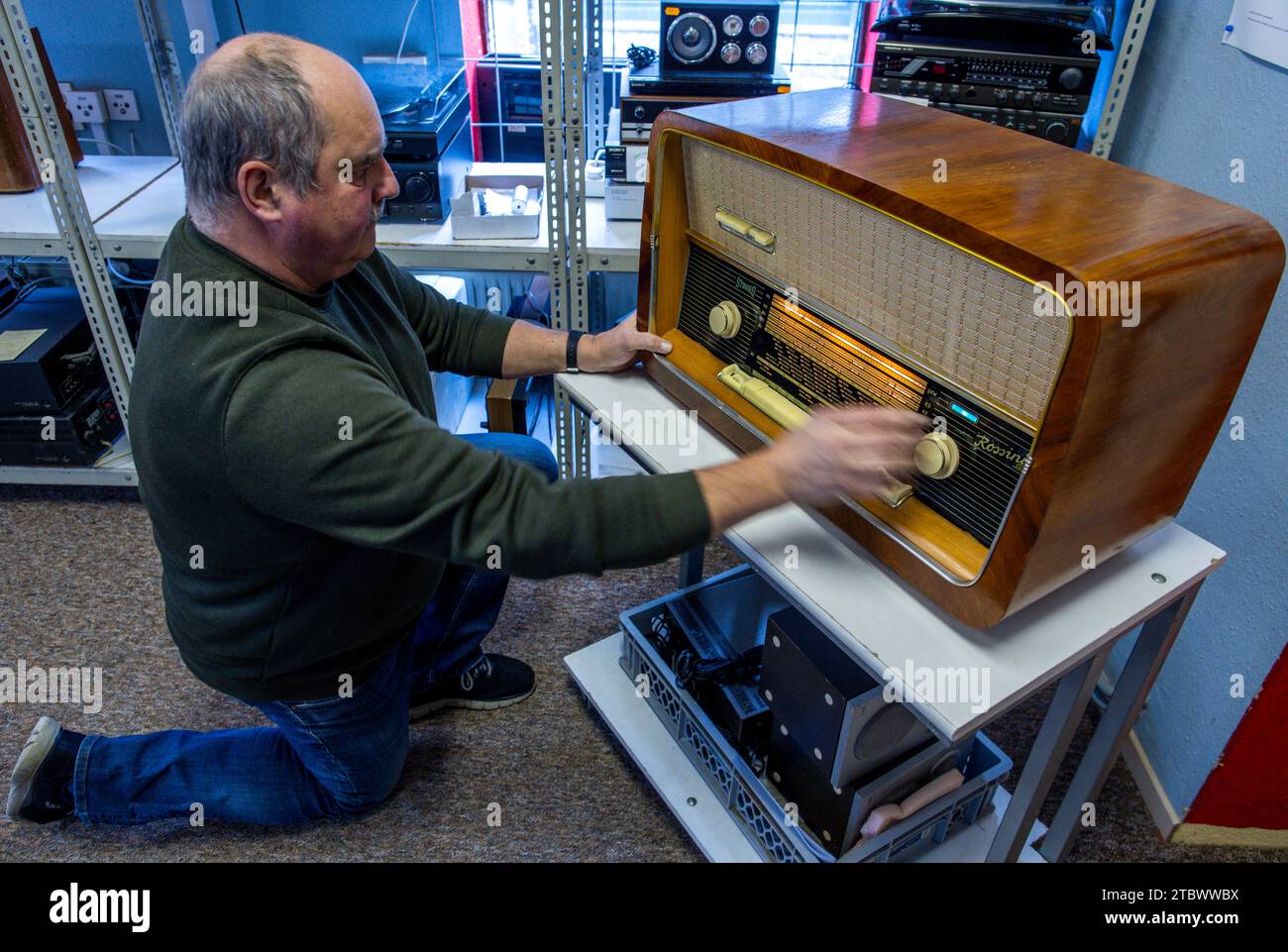 Schwerin, Germany. 28th Nov, 2023. Jens-Uwe Peters adjusts a radio frequency on the fully functional 'Rossini' tube radio from the 1950s. Along with many other historical devices, it is waiting for a buyer in a small workshop for old radios, record players and hi-fi systems. Small electrical appliances from East and West have been restored to working order here for around 34 years. It is mainly regular customers with a soft spot for GDR radio technology who hand in their equipment to the trained radio and television technician. A lack of spare parts and dec Credit: dpa/Alamy Live News Stock Photo