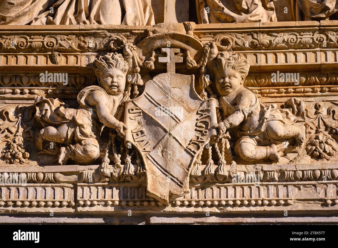 Ancient art or stone carvings of angels holding a coat of arms. Medieval architecture in the former Hospital de Santa Cruz Stock Photo