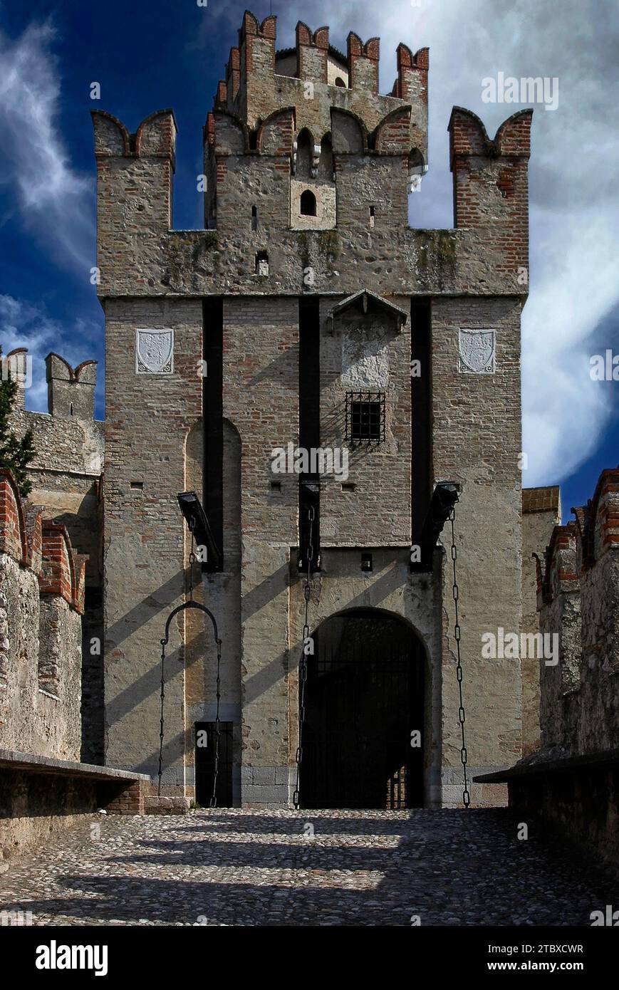 Southern entrance, with drawbridges lowered, to the Castello Scaligero or Rocca Scaligera, at Sirmione on Lake Garda in Lombardy, Italy.  Built in the 1300s and surrounded by a natural moat, the castle takes its name from the Della Scala family, ruling dynasty in Verona, who dominated the area at the time.  It is one of the best-preserved Scaliger fortresses. Stock Photo