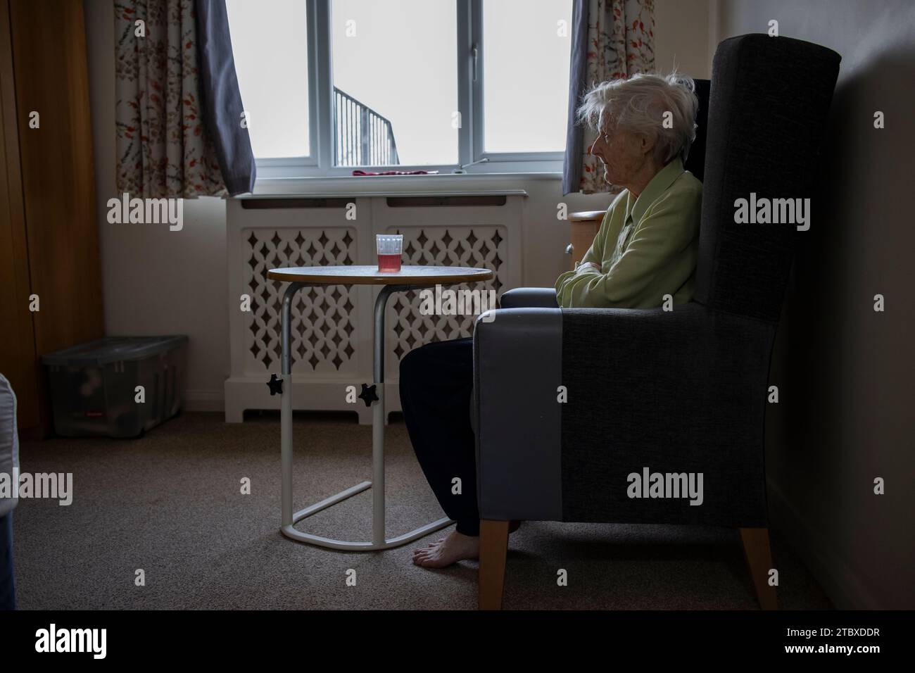 Elderly lady in her 80's sits alone in her social care home bedroom, England, United Kingdom Stock Photo