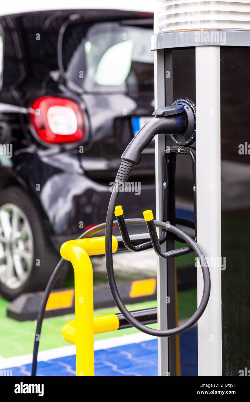 Electric car with plug-in socket at charge station charging battery Stock Photo