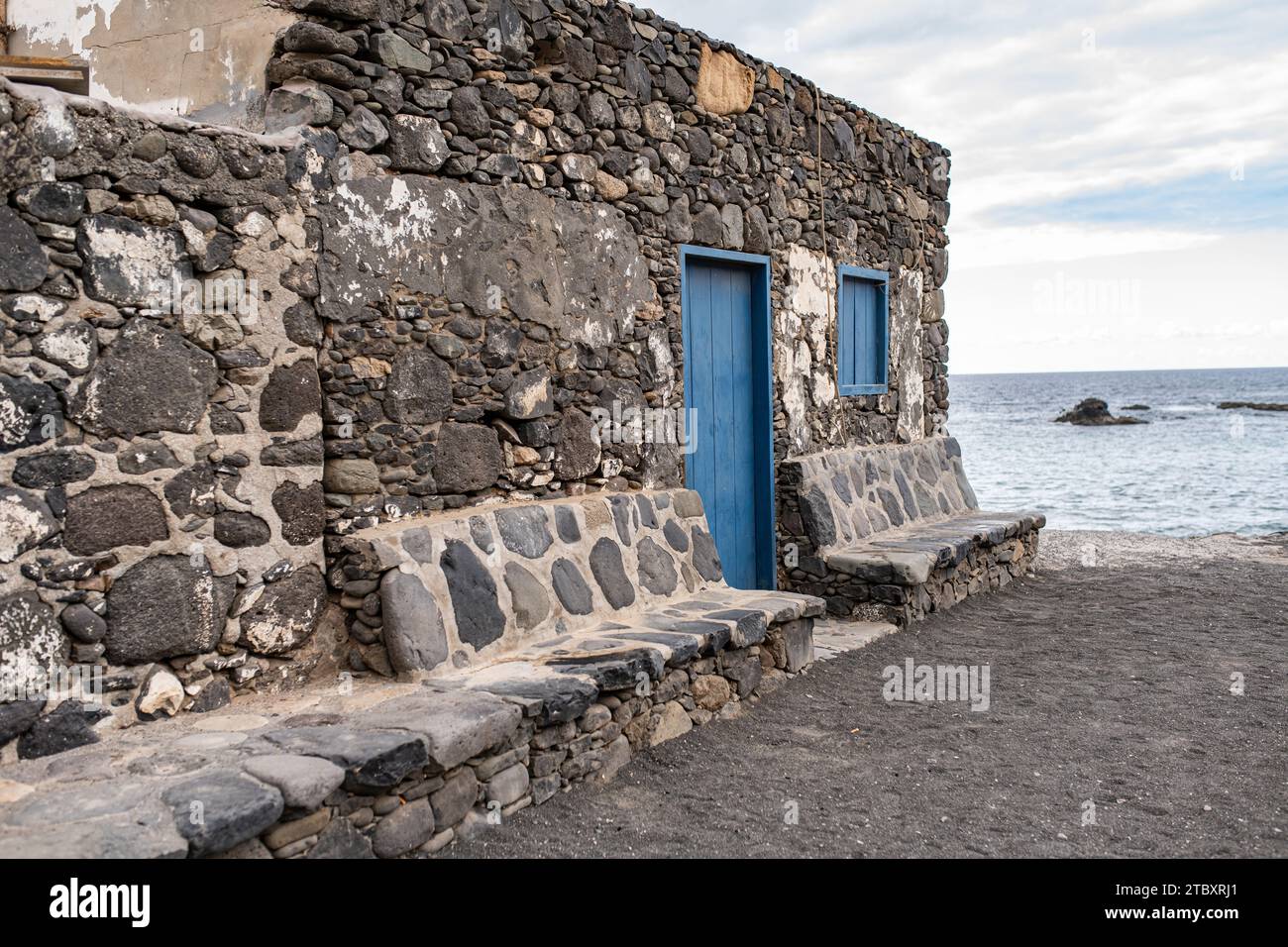 A house with blue doors and stone benches with a view on the ocean. Fuerteventura, Canary Islands. Stock Photo