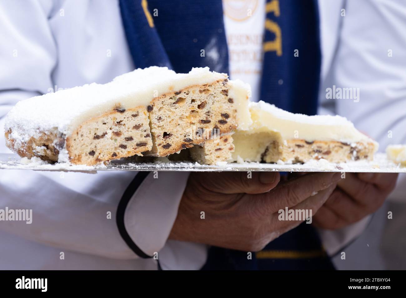 Dresden, Germany. 09th Dec, 2023. Master baker Rudolf Maaß holds a piece of the Dresden Giant