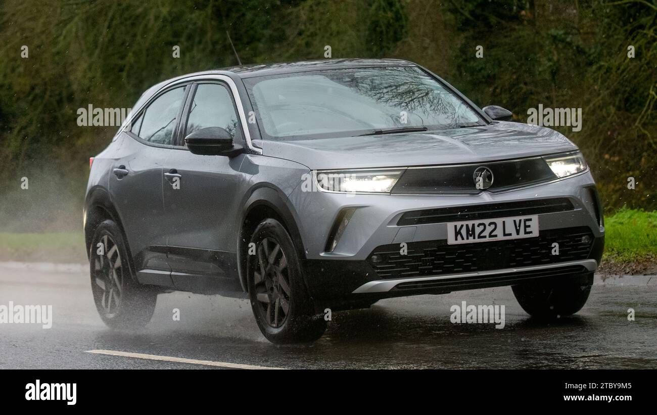 Milton Keynes,Bucks,UK - Dec 9th 2023: 2022 grey Vauxhall Mokka car driving on a wet road, in the rain with headlights on Stock Photo