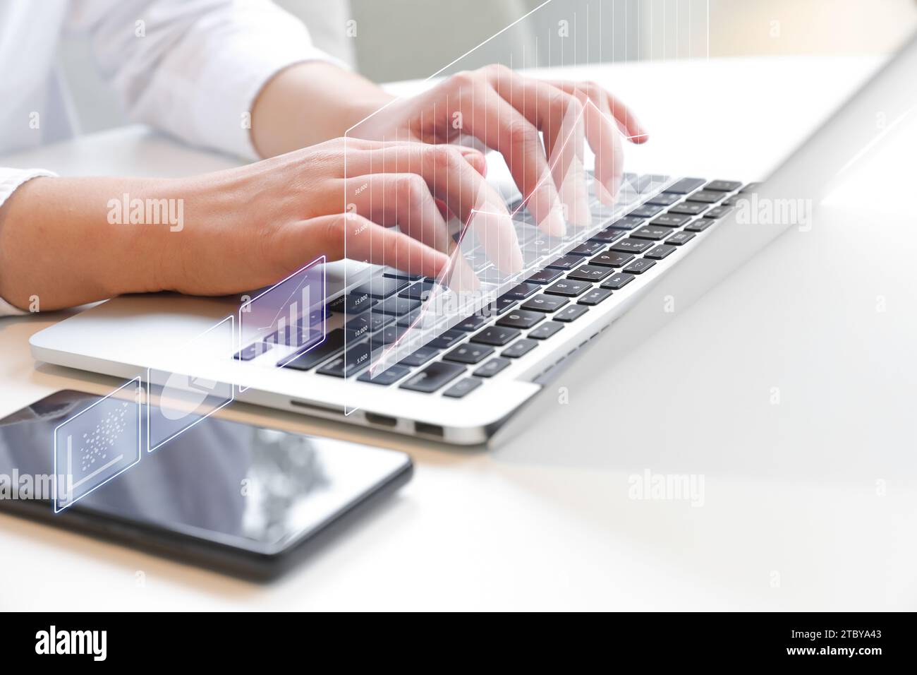 Two hands typing on laptop at desk (finance, investment related holographic projection) Stock Photo