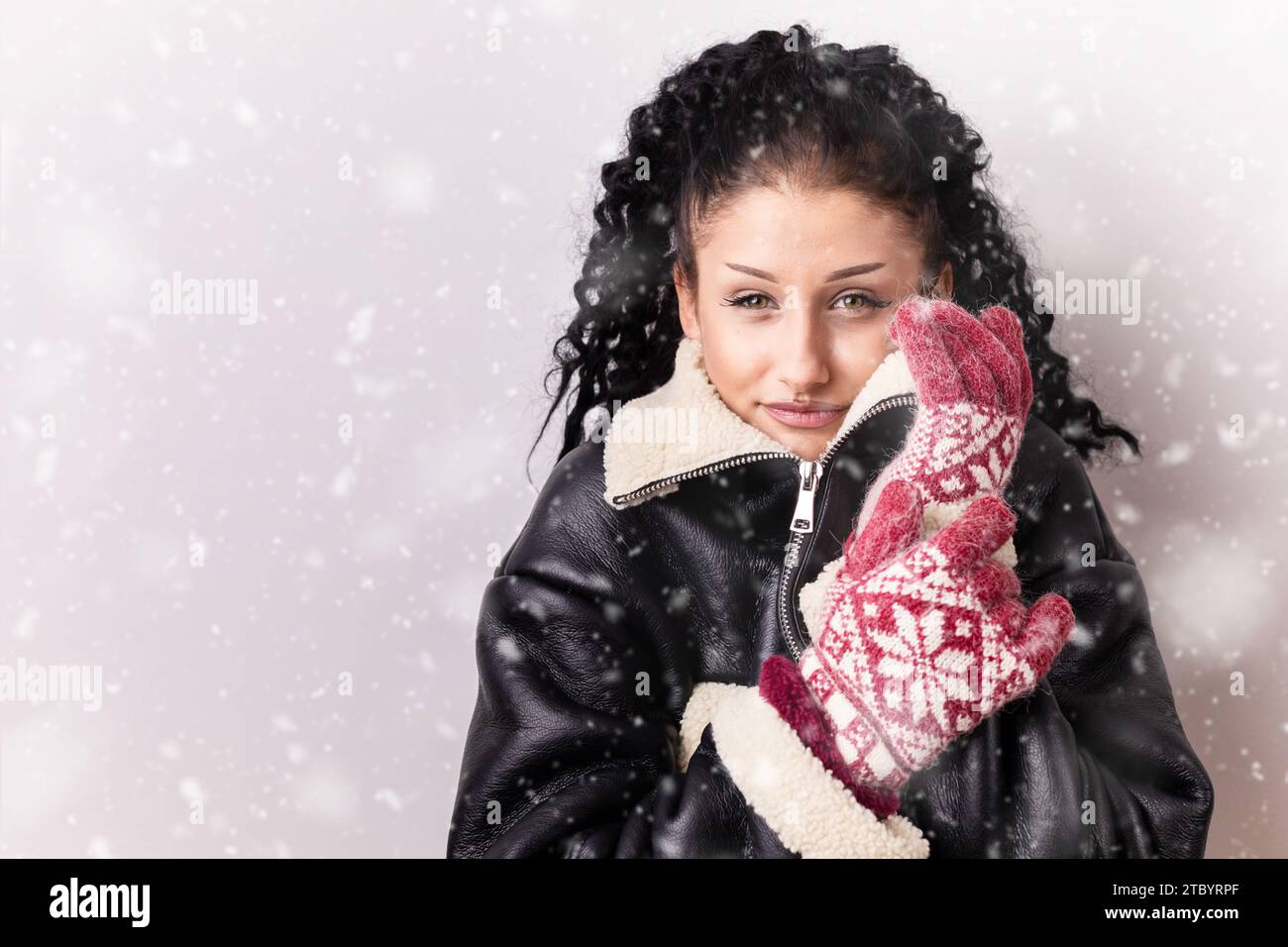 Young, brunette, curly girl in the leather jacket looking like she is freezing. Copy space Stock Photo
