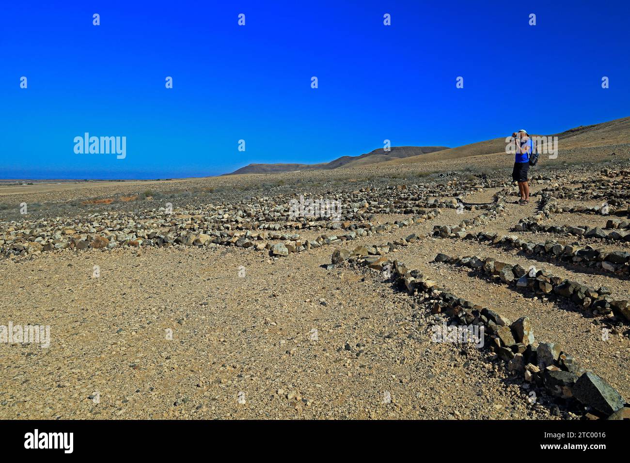 Photographer at Wolf Patton's Labyrinth - low stone maze in the middle of nowhere near El Cotillo, Fuerteventura, Canary Islands, Spain. Nov 2023 Stock Photo
