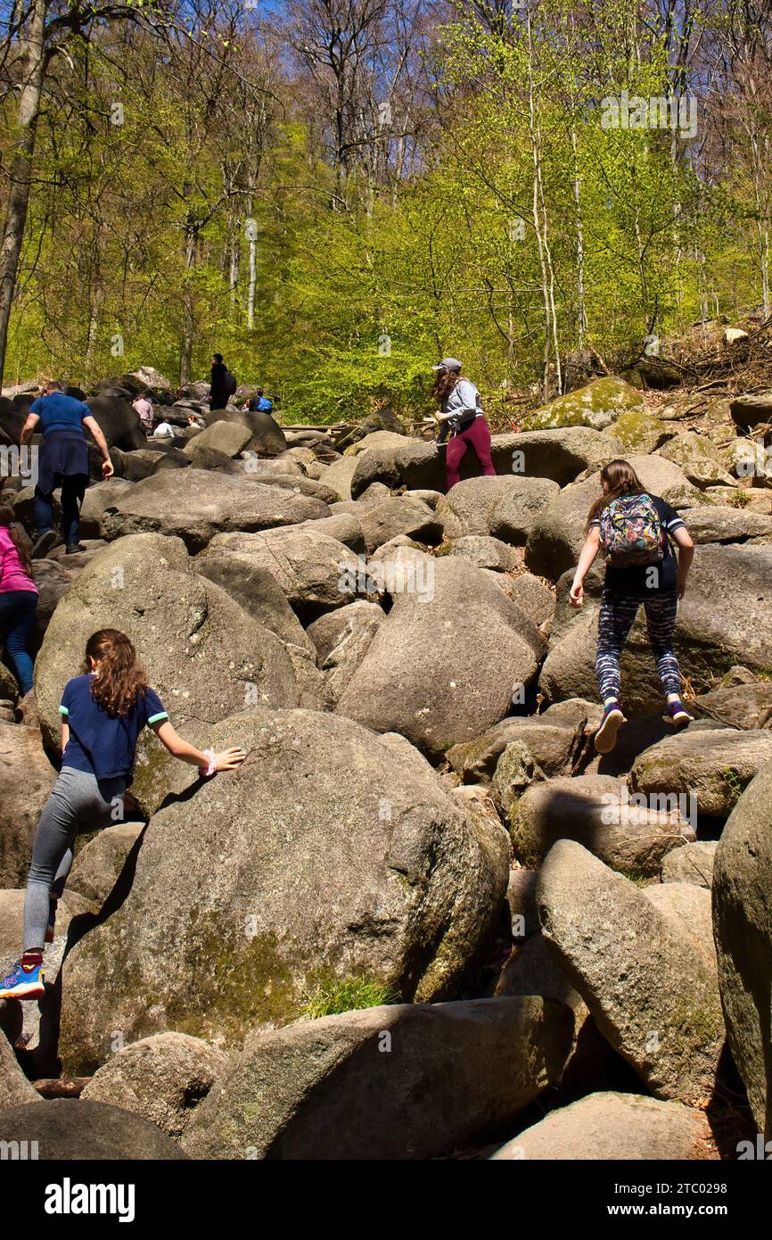 Lautertal, Germany - April 24, 2021: People climbing on large rocks on a hill at Felsenmeer on a spring day in Germany. Stock Photo