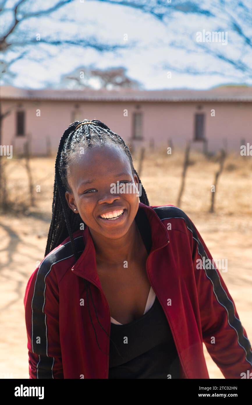 portrait of village young african woman with braids, outdoors setting ...