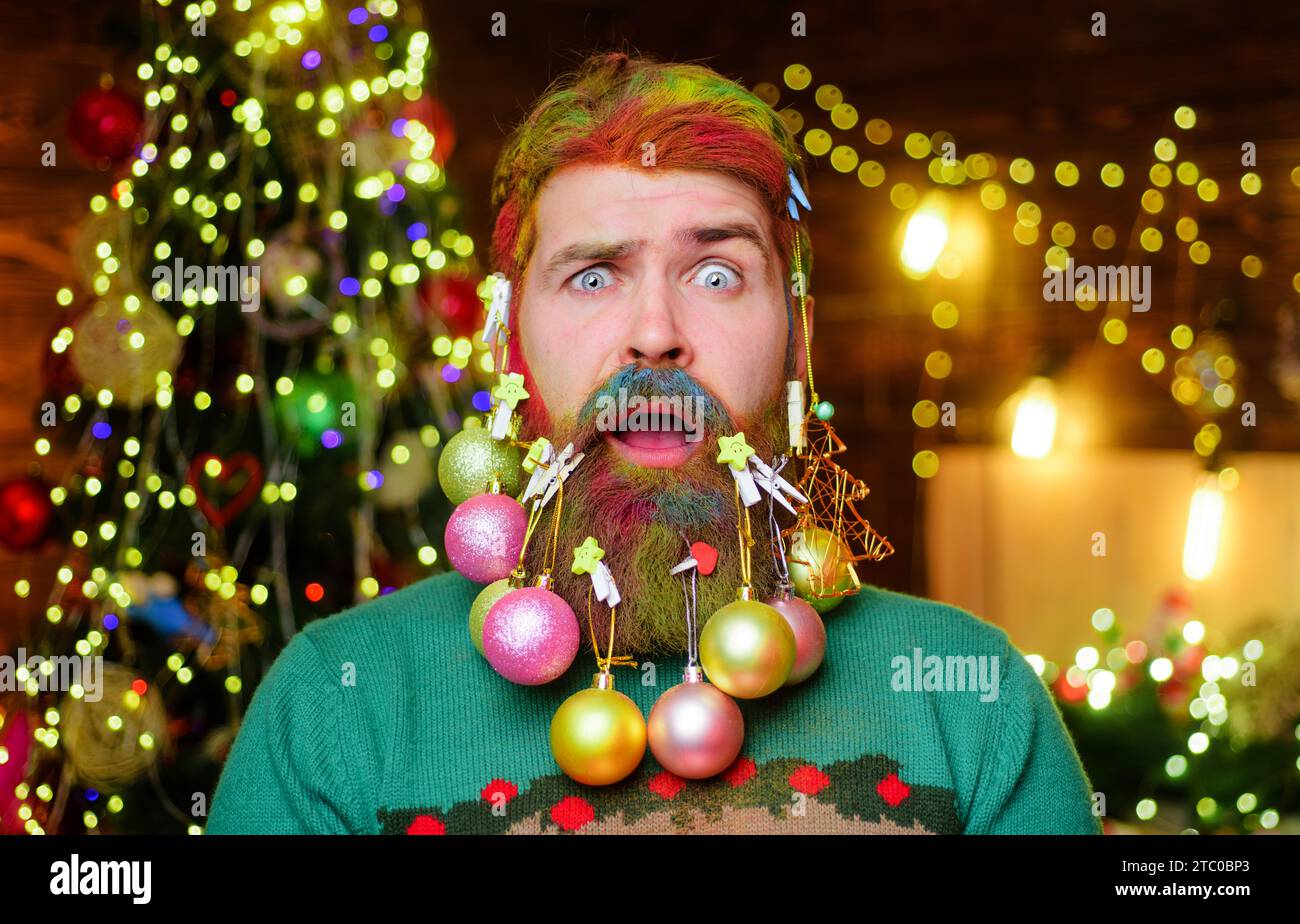 Closeup portrait confused man with decoration colorful balls in beard. Christmas beard decorations. Bearded man with decorated Christmas beard for New Stock Photo