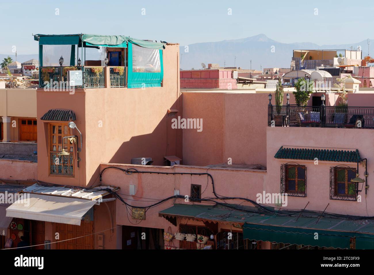 Elevated cityscape view across the rooftops with restanrant in Marrakesh aka Marrakech with mountains behind, Morocco, December 09, 2023 Stock Photo