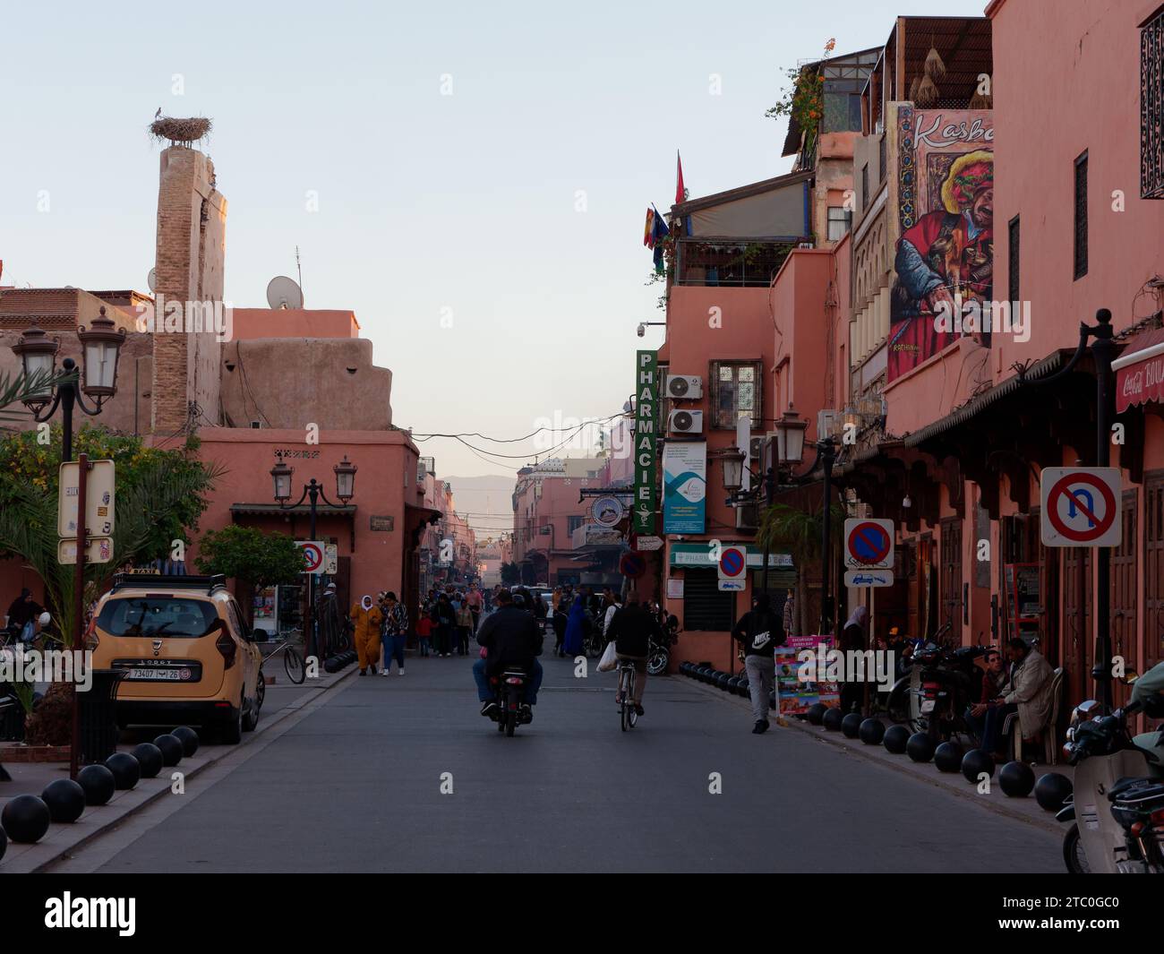 Busy street at sunset in the Kasbah area of Marrakesh aka Marrakech, with a birds nest atop a column. Morocco, December 09, 2023 Stock Photo