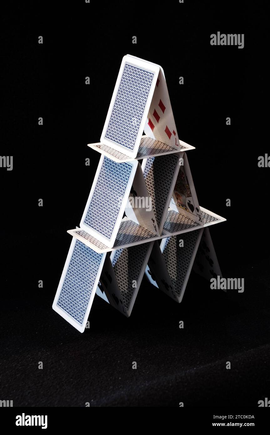 A house of cards in balance on black background Stock Photo