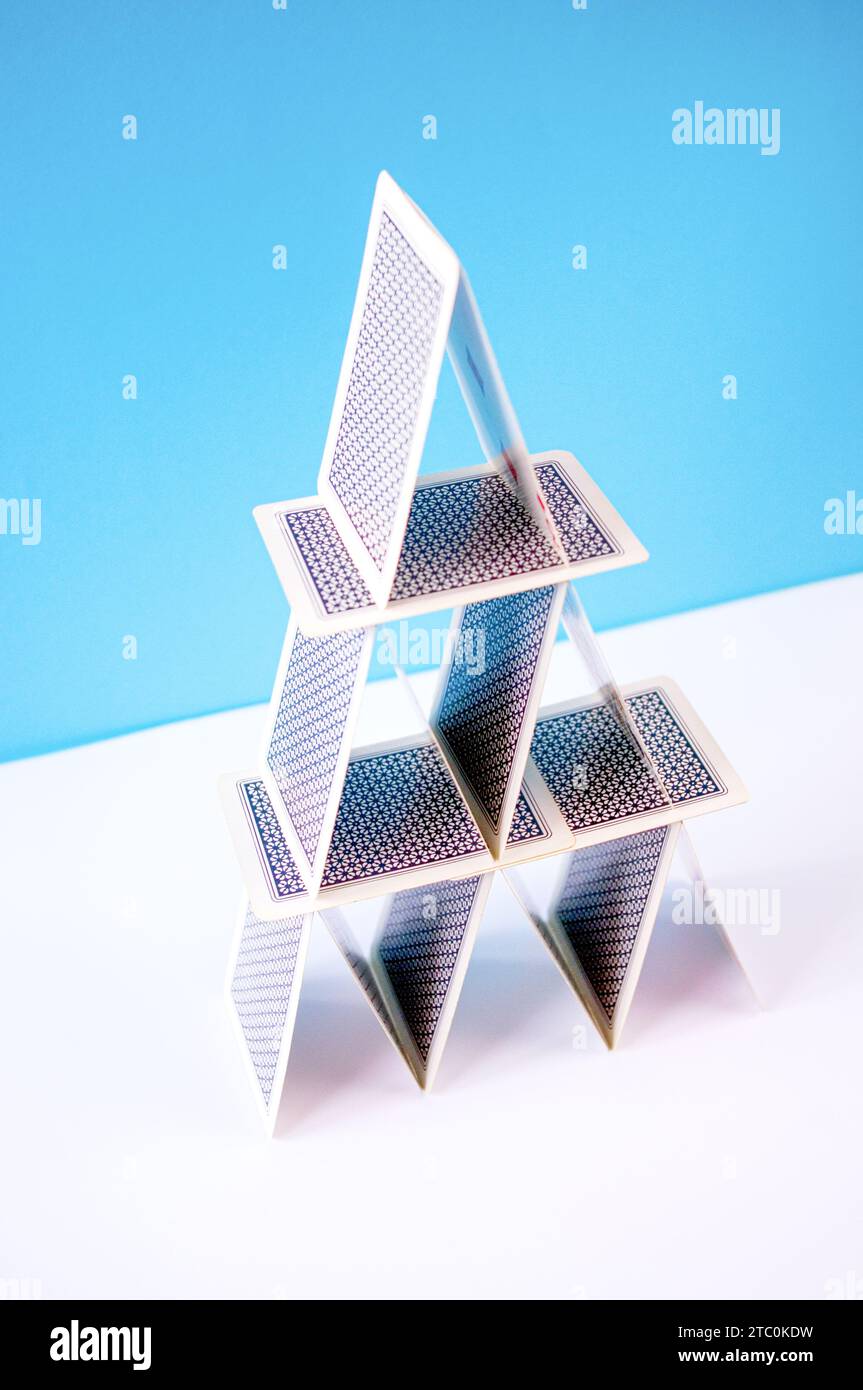 Playing card pyramid in balance made with poker cards on a blue background. Stock Photo