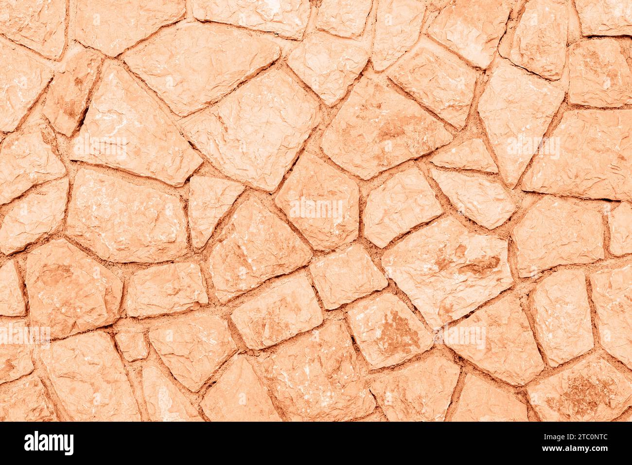 Old grunge stone wall background, texture. Demonstrating color of the year 2024 Peach Fuzz. Stock Photo