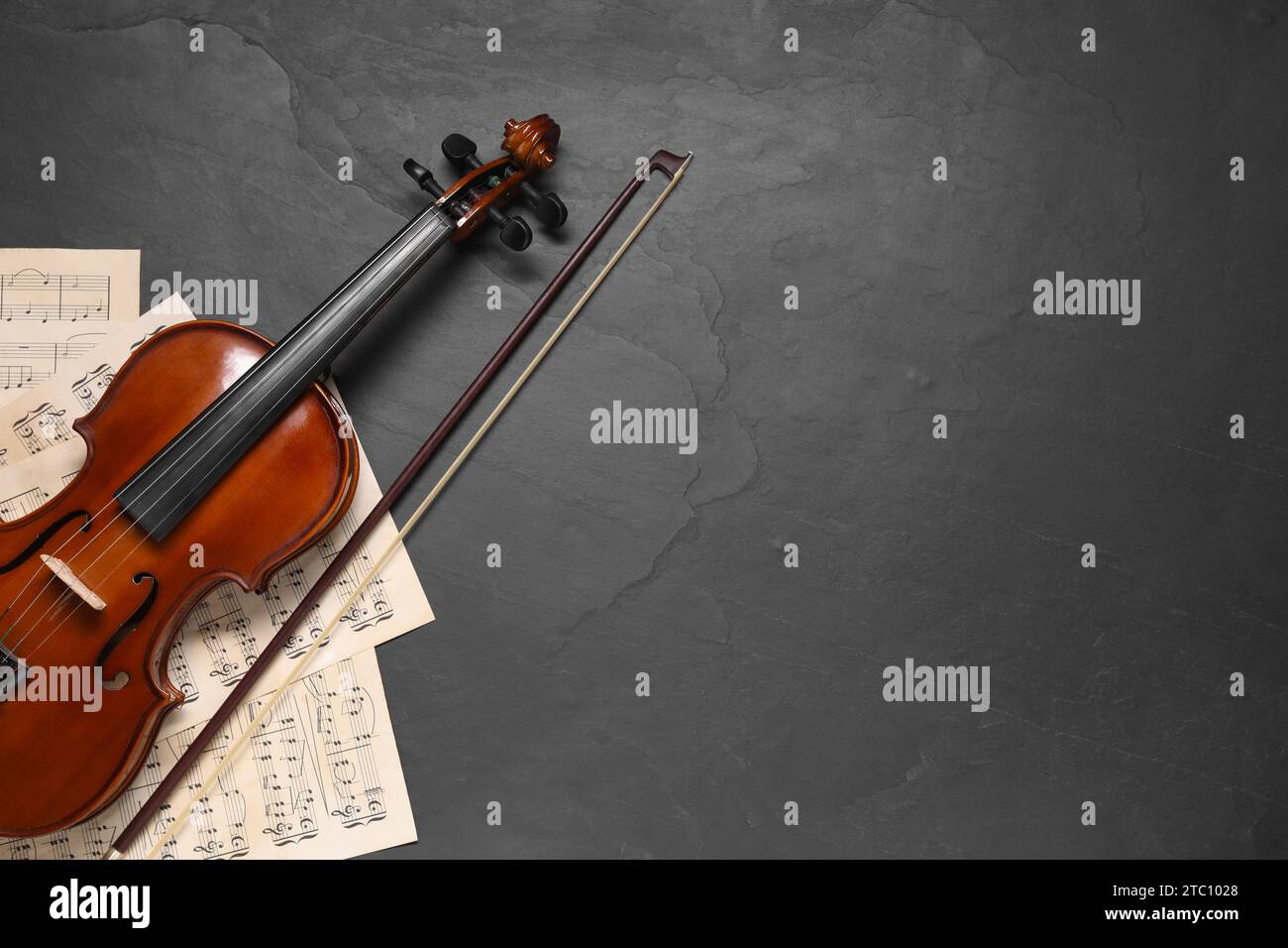Violin, bow and music sheets on black table, top view. Space for text Stock Photo