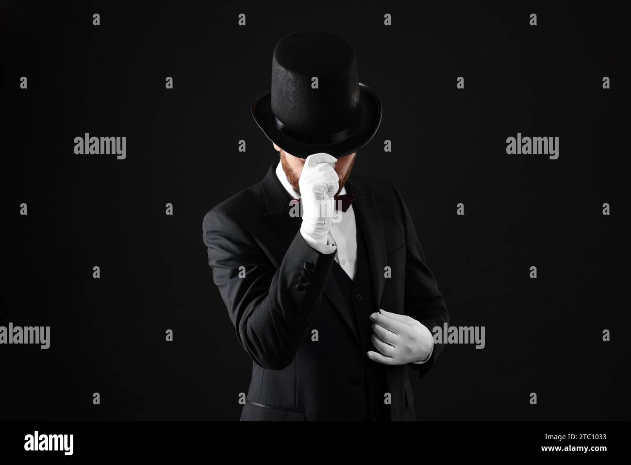 Magician in top hat on black background Stock Photo - Alamy