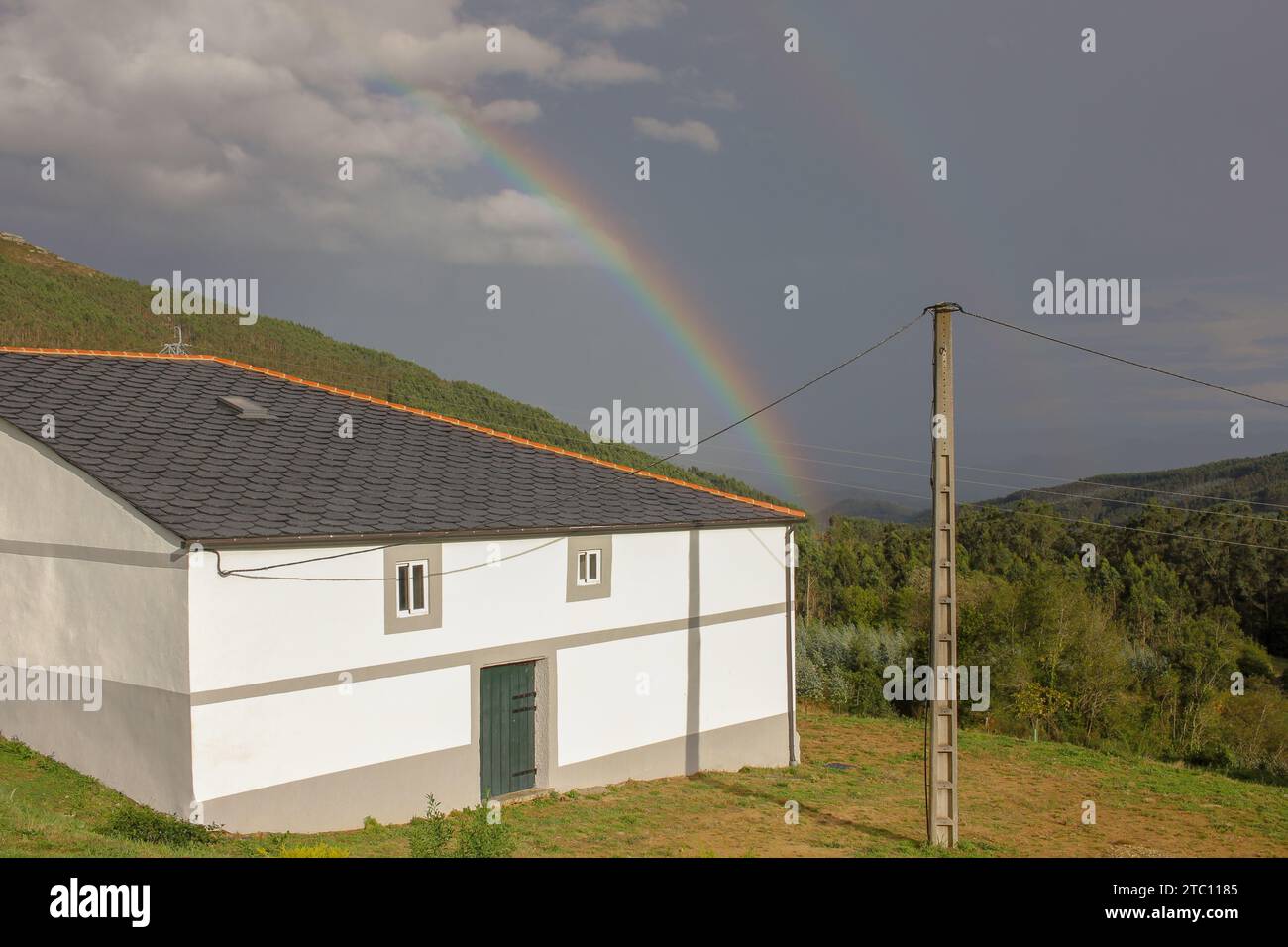 rainbow over a house in the mountains in Galicia, Spain Stock Photo
