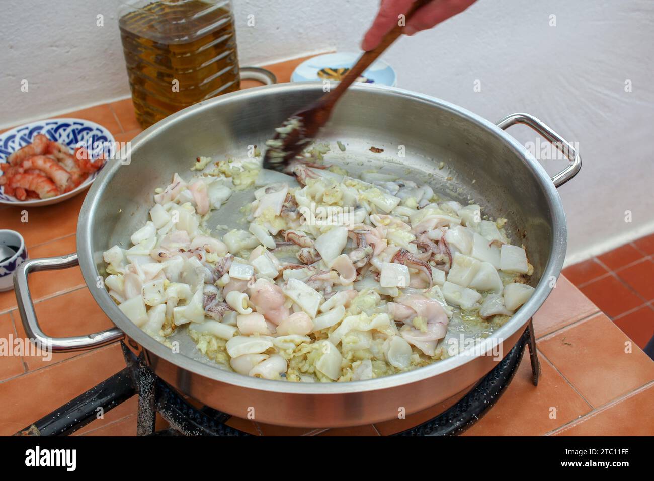 Seafood Symphony: Preparing a Savory Black Rice Dish with Wooden Spoon Stock Photo