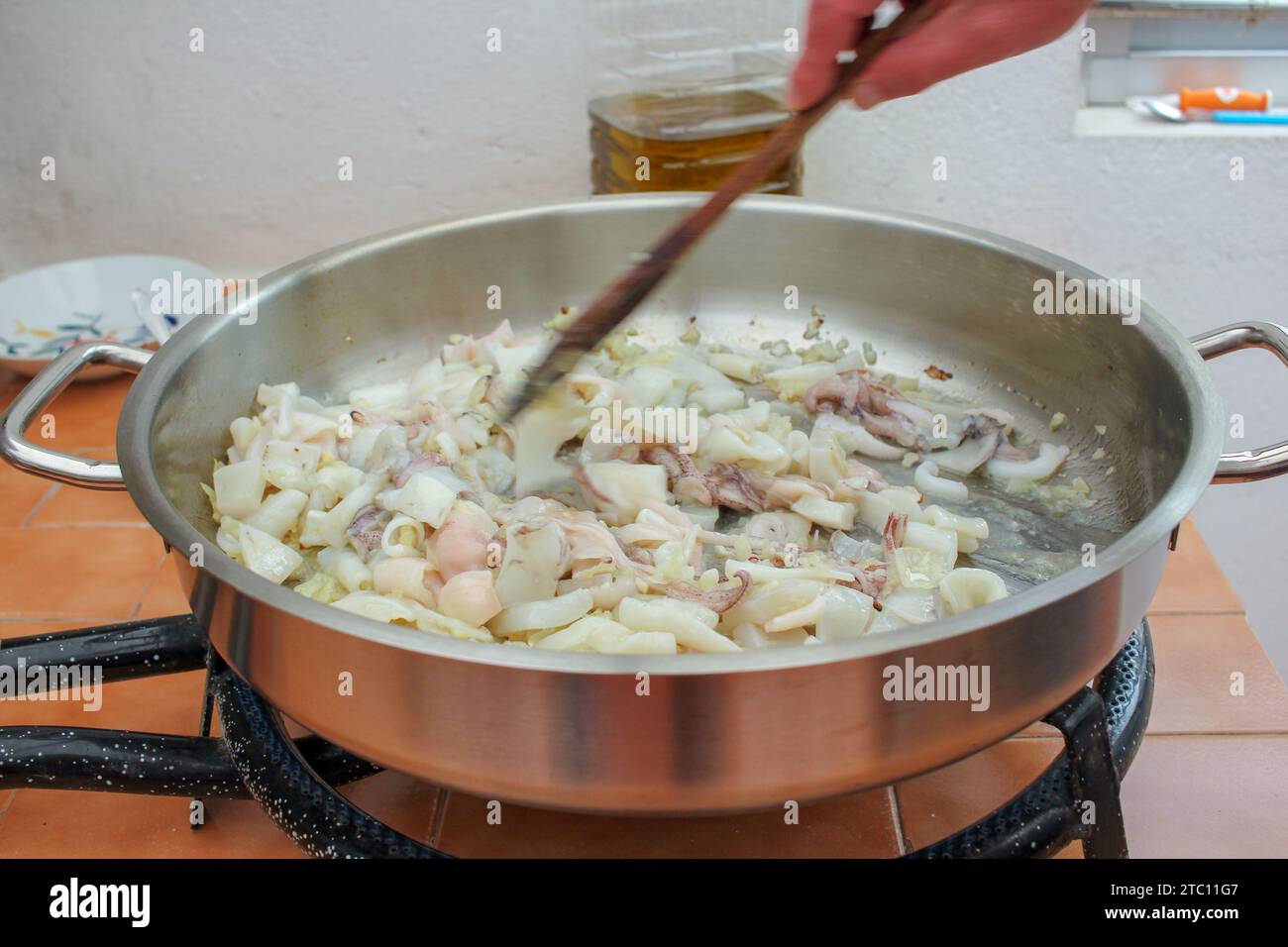 Seafood Symphony: Preparing a Savory Black Rice Dish with Wooden Spoon Stock Photo