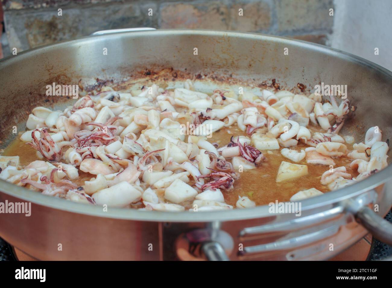 Seafood Symphony: Preparing a Savory Black Rice Dish with Wooden Spoon Stock Photo
