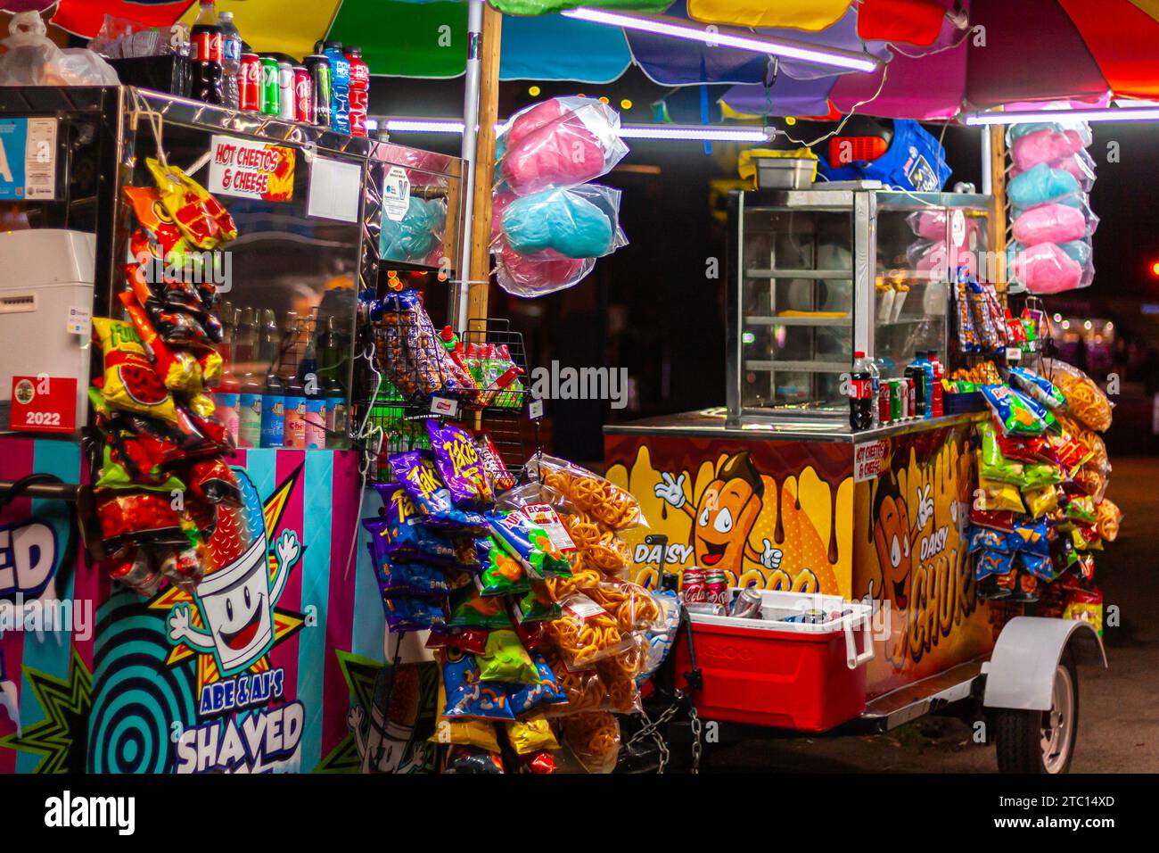 Colorful snack carts at night with cotton candy, chips, shaved ice, and sodas Stock Photo