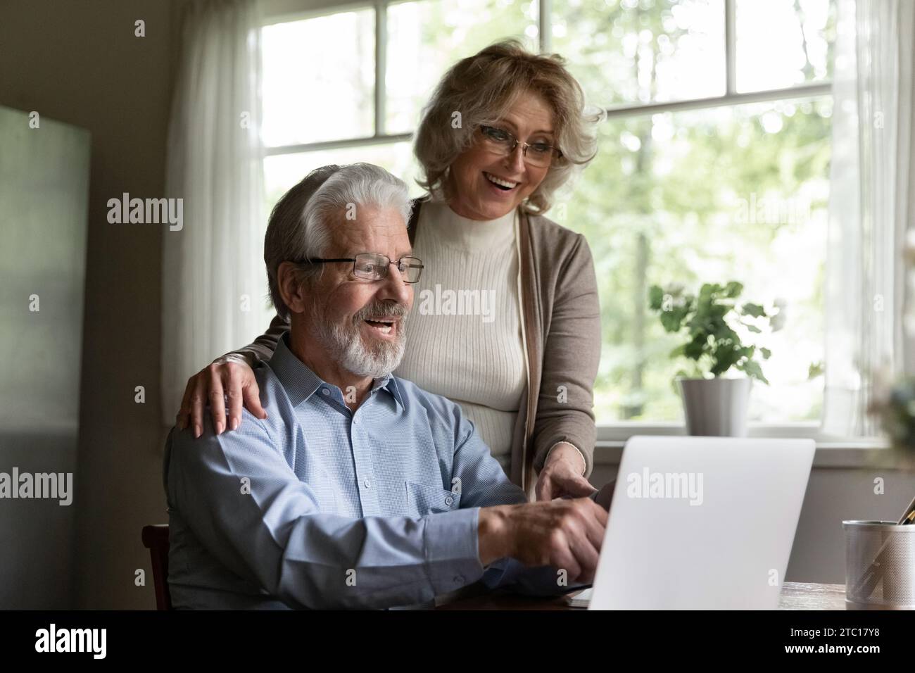 Amazed elderly married couple hug point fingers on pc screen Stock Photo