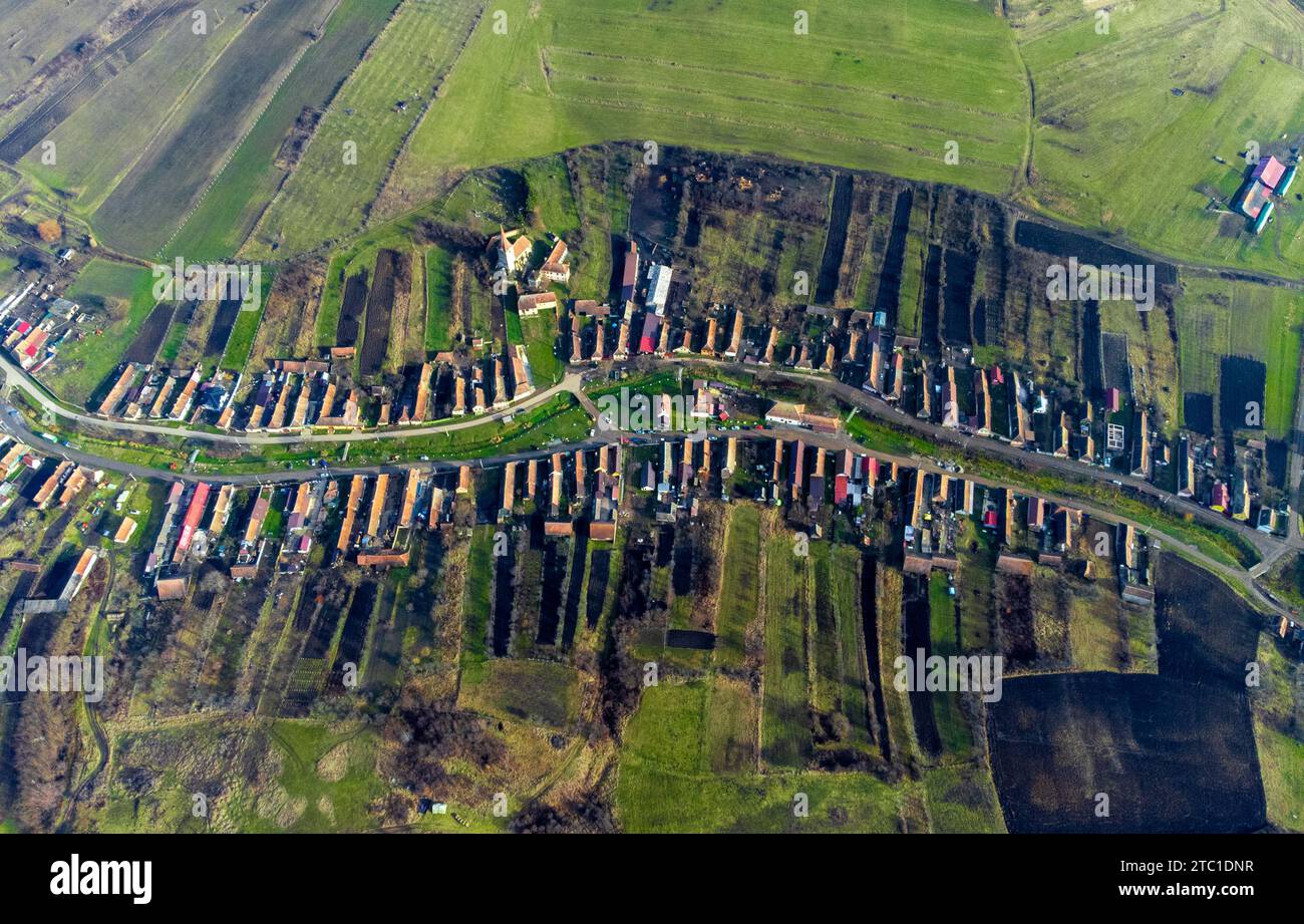 An aerial view of a picturesque village in Romania surrounded by lush green hills. Stock Photo