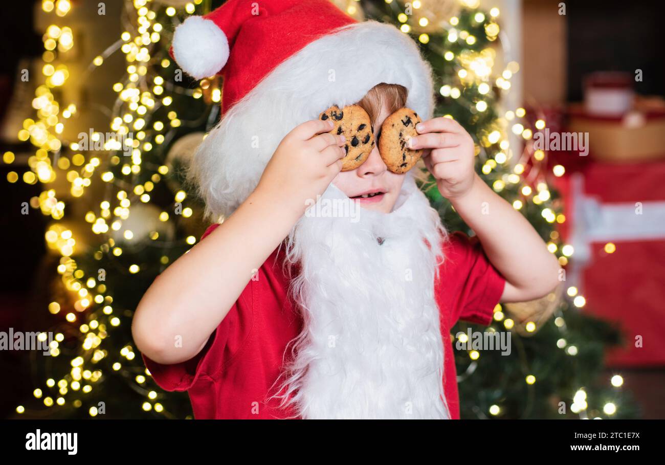 Portrait of Santa Claus Drinking milk from glass and holding cookies. Christmas Beard style. Merry Christmas. Santa boy in Santa hat. Christmas food Stock Photo
