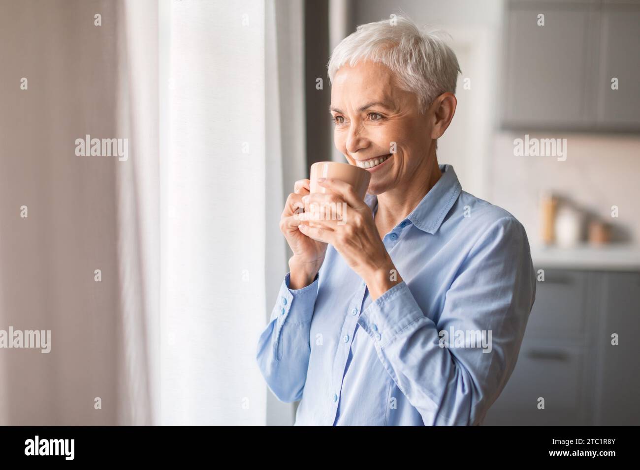Relaxed smiling mature woman drinking coffee at home Stock Photo