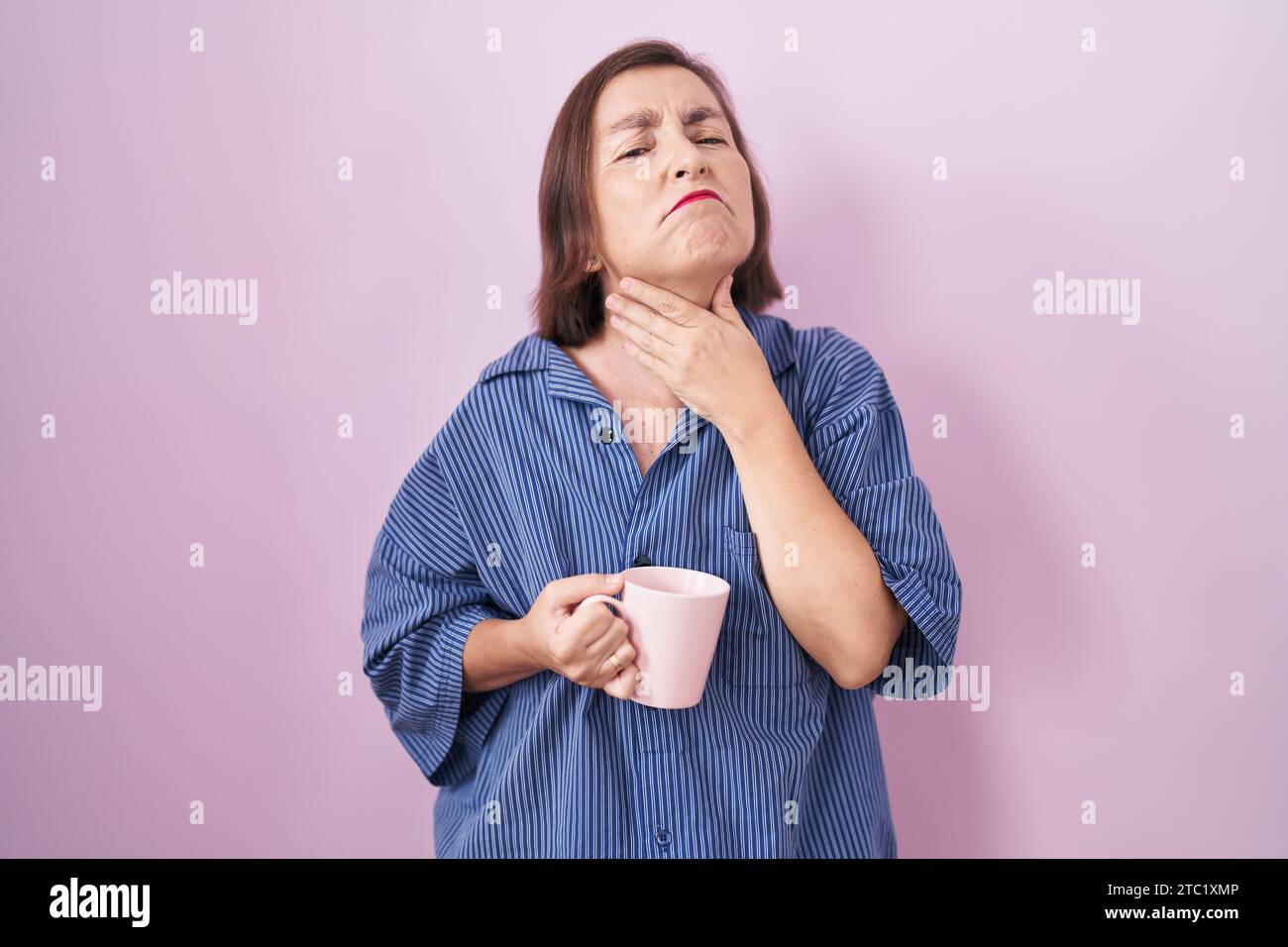 Middle age hispanic woman drinking a cup coffee touching painful neck