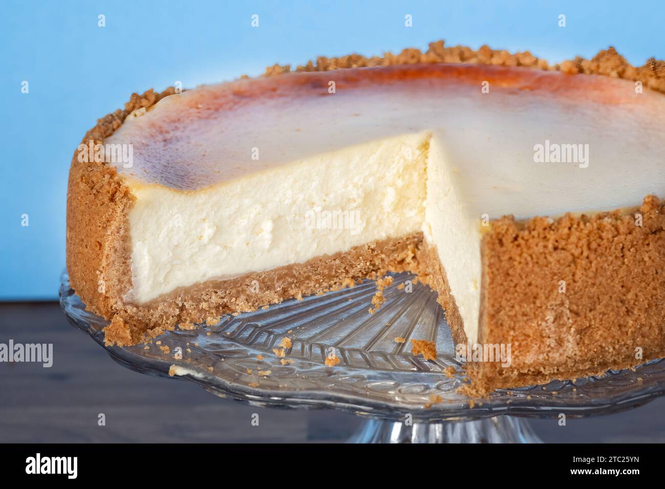 A whole deep filled authentic New York style cheesecake on a glass cake ...