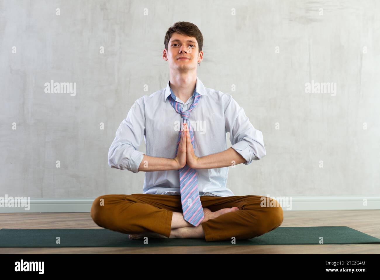 Young guy office worker doing yoga in studio Stock Photo - Alamy