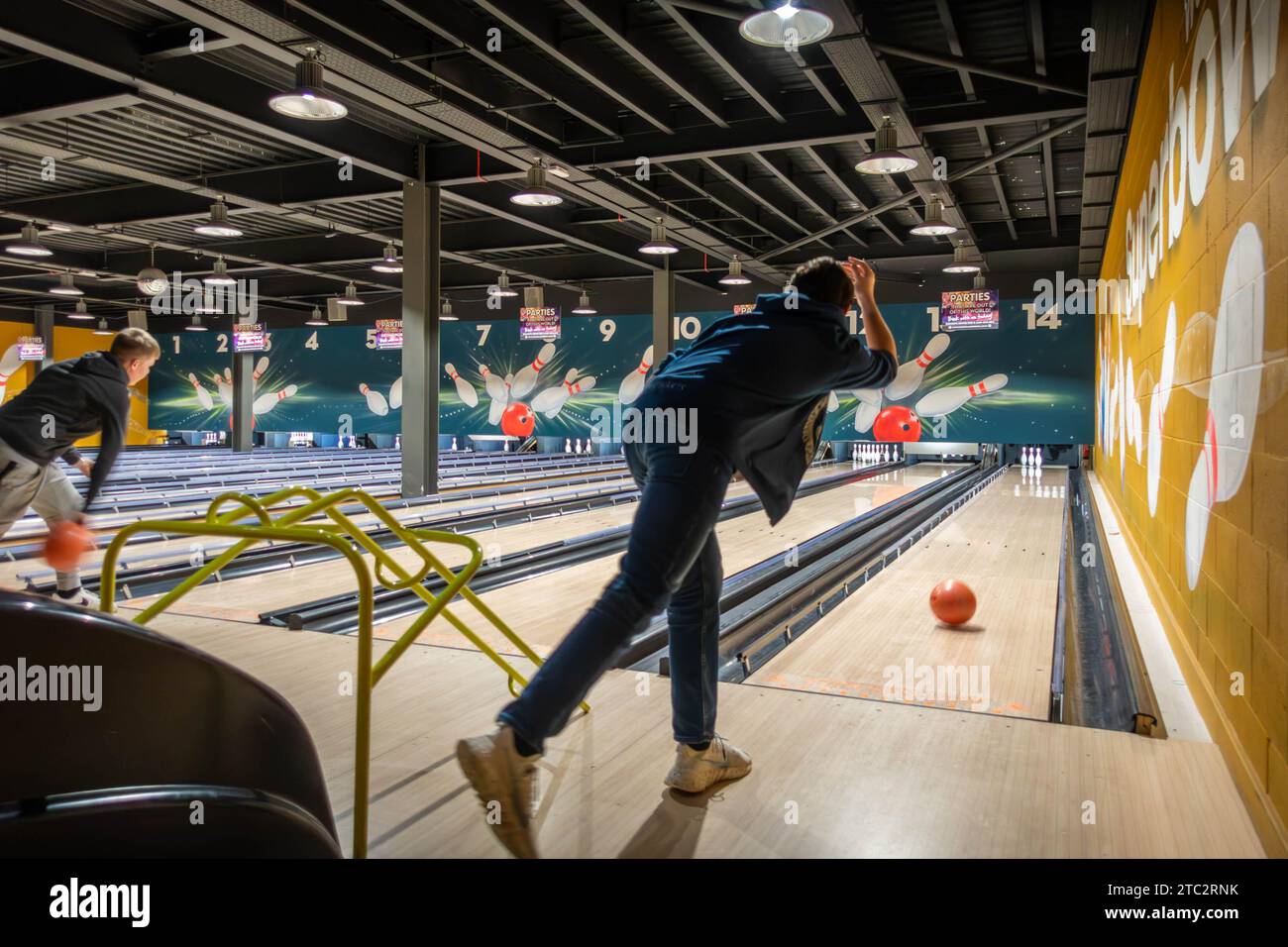 A teenager bowls a bowling ball down a lane at a 10-pin bowling alley Stock Photo