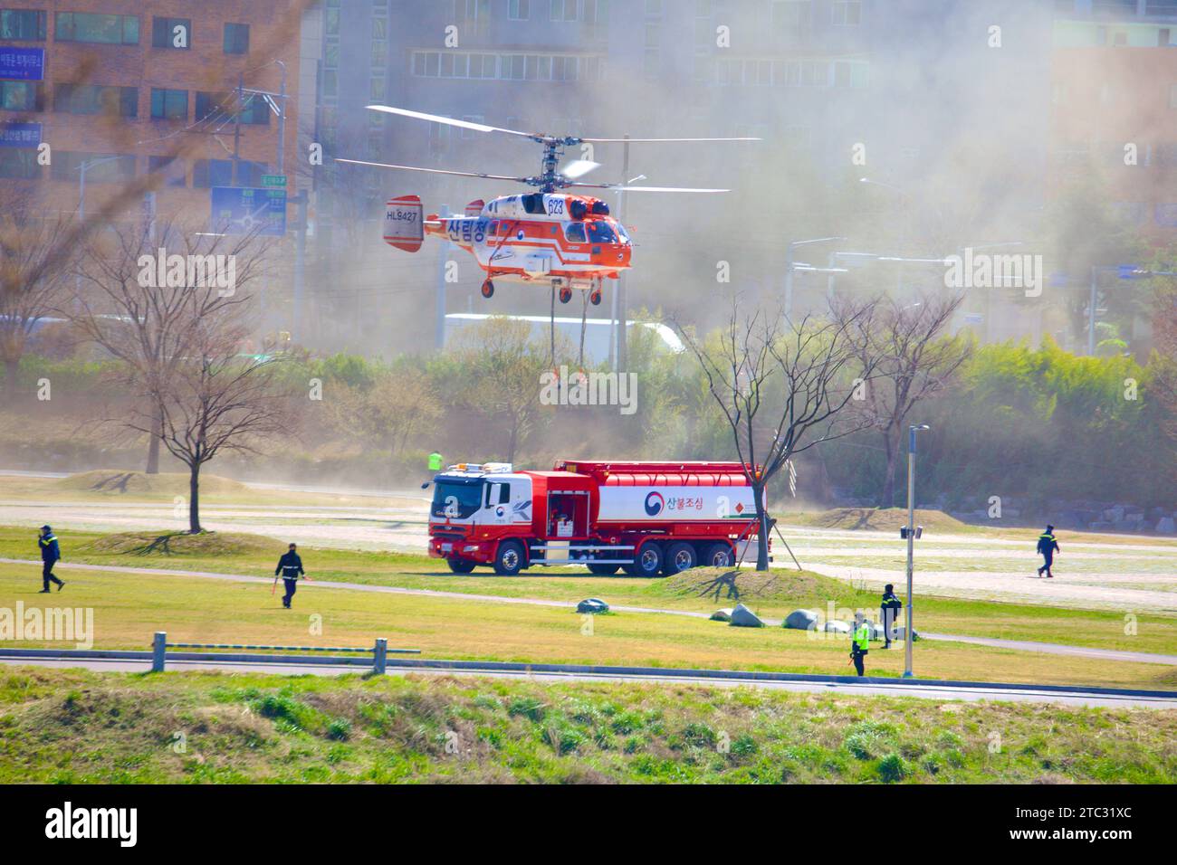 A firefighting helicopter makes a dramatic landing at Taehwa Park, kicking up clouds of dust, showcasing the dynamic nature of emergency aviation. Stock Photo