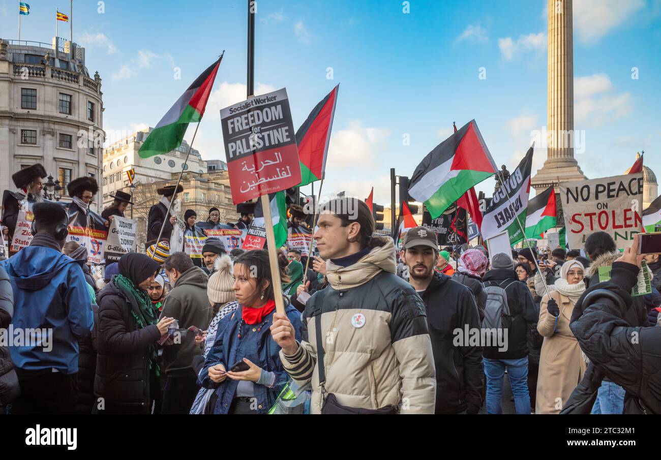 London / UK - Dec 9 2023: Pro-Palestinian protesters march past members of the anti-Zionist Haredi Jewish group Neturei Karta, or Guardians of the Cit Stock Photo