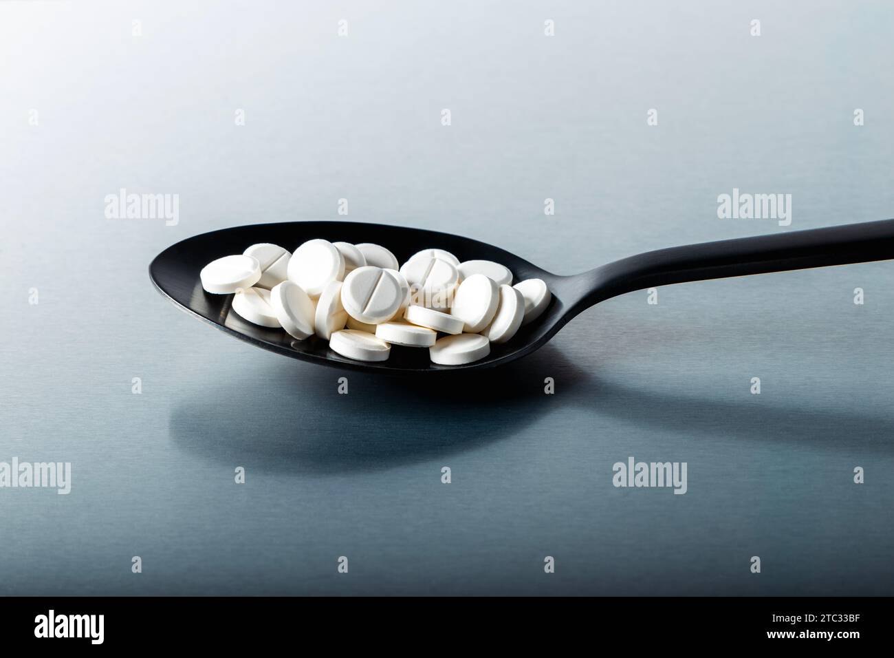 White pill tablets on a black spoon Stock Photo