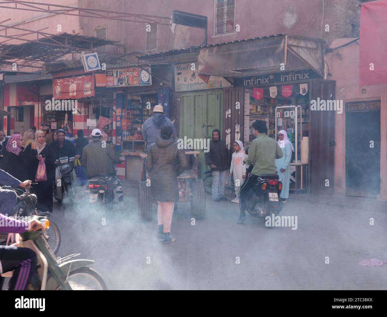Dusty street with shops and motor bikes in the Medina in Marrakesh aka Marrakech with Mosque in the distance, Morocco, December 10, 2023 Stock Photo