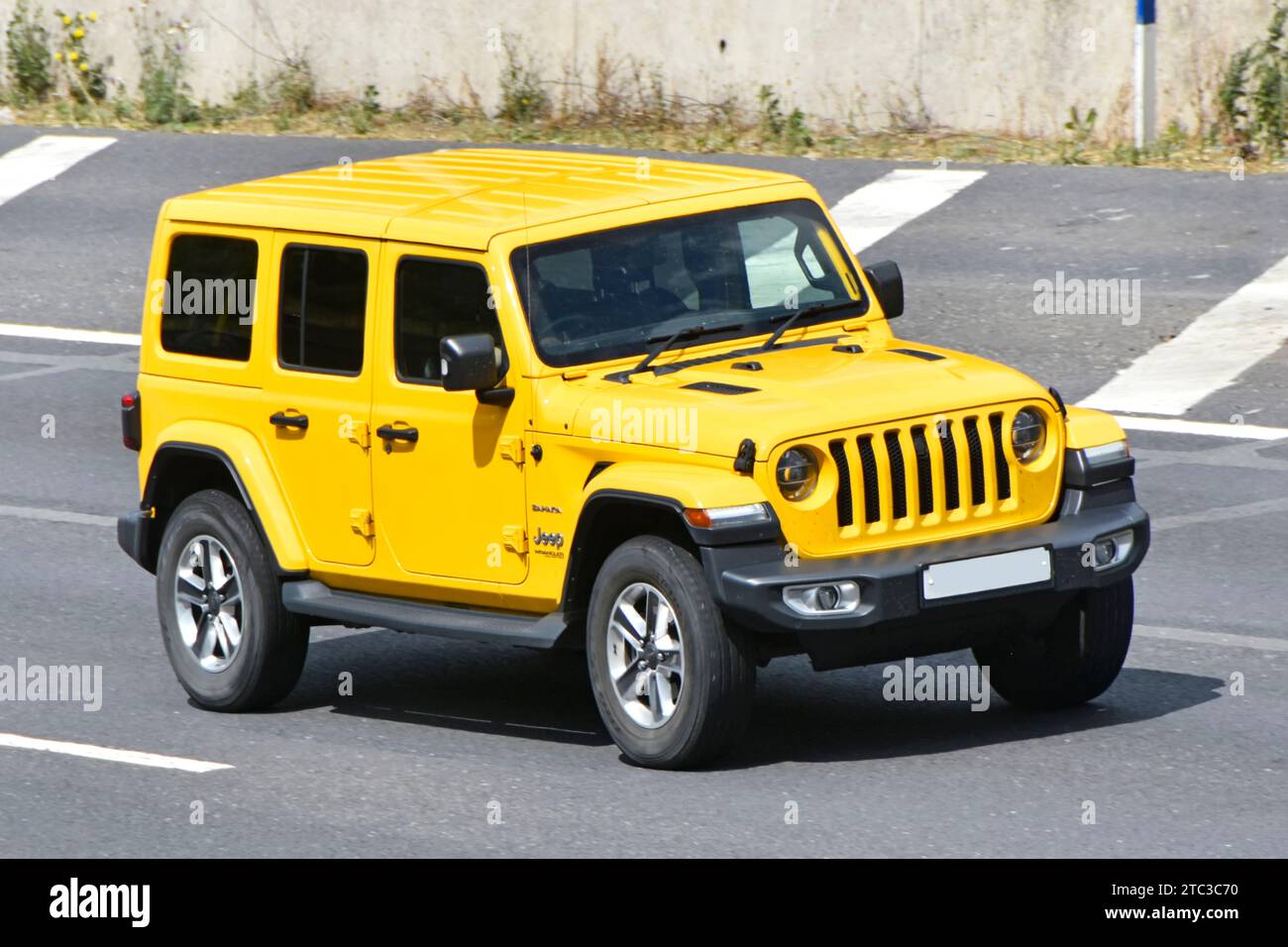 JEEP Wrangler Sahara 4x4 wheel drive roof side front view bright yellow moving & driving along London orbital route on M25 motorway Essex England UK Stock Photo