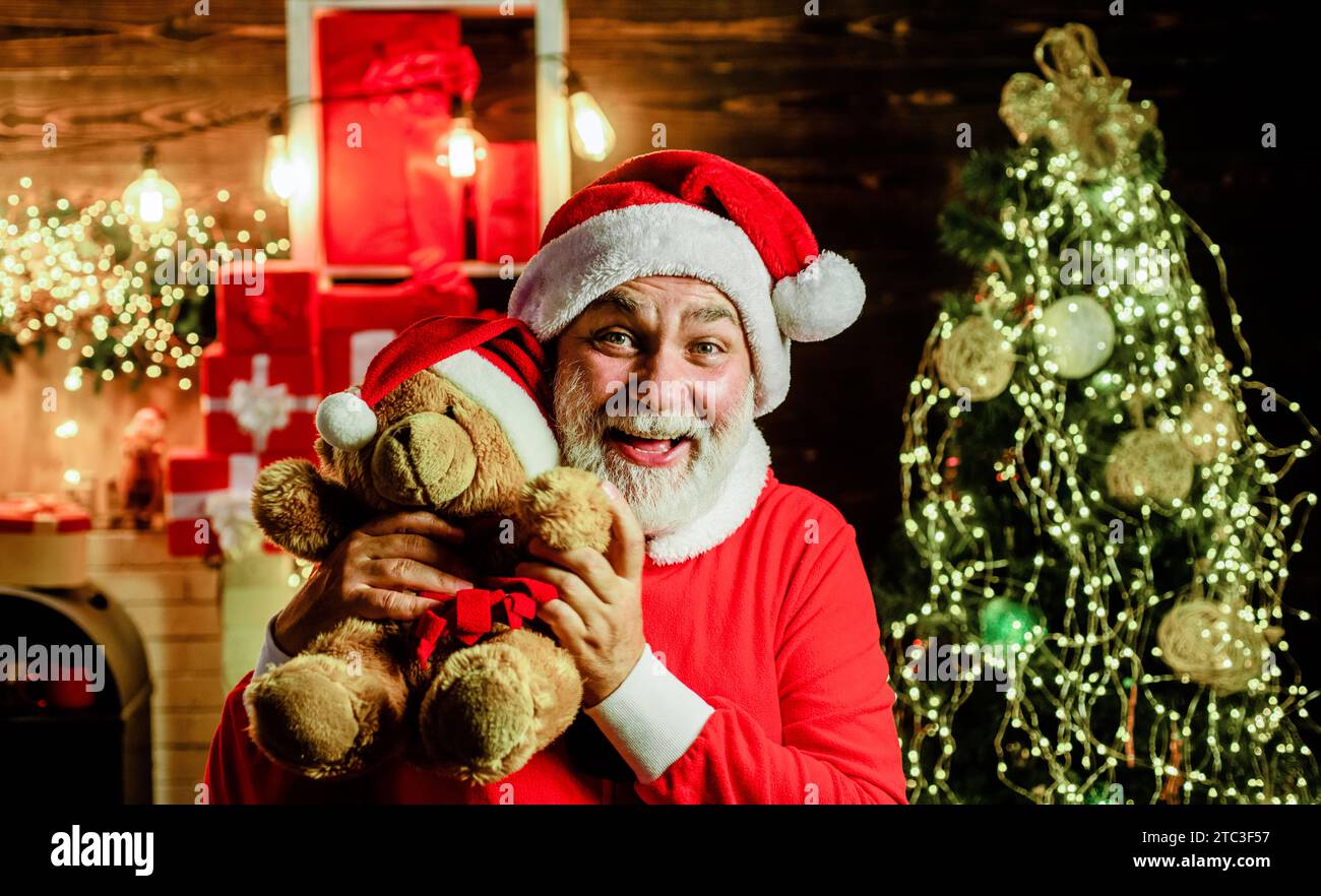 Happy Santa Claus with teddy bear. Christmas gift and present to cute kids. Winter season. Holiday shopping online. Bearded man in Santa Claus suit Stock Photo