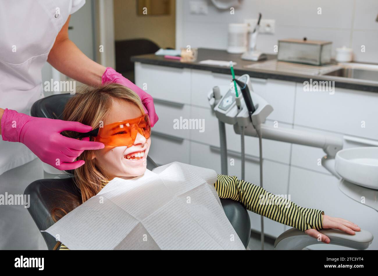 Dentist doctor wearing protective eyeglasses to little girl during