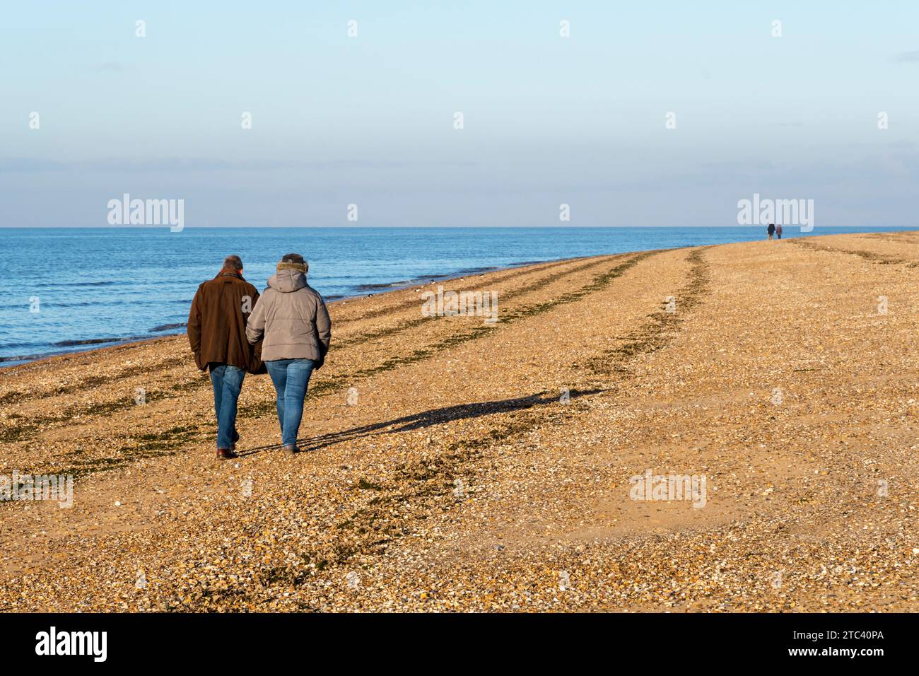 People walking along the shore of the Wash in west Norfolk on bright winter's day. Stock Photo
