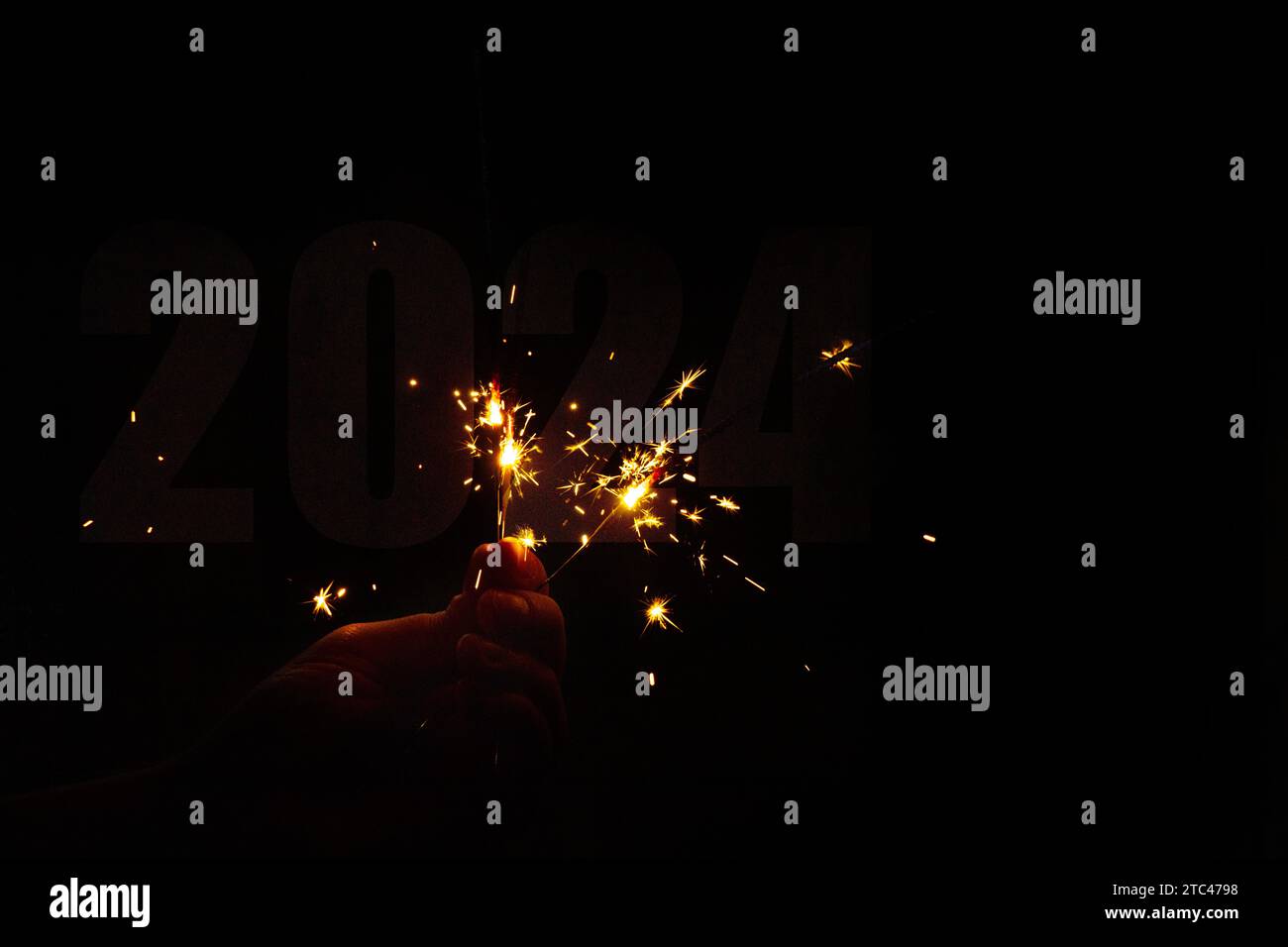 Male hand hold sparklers and text 2024, Happy New Year 2024, holiday Stock Photo