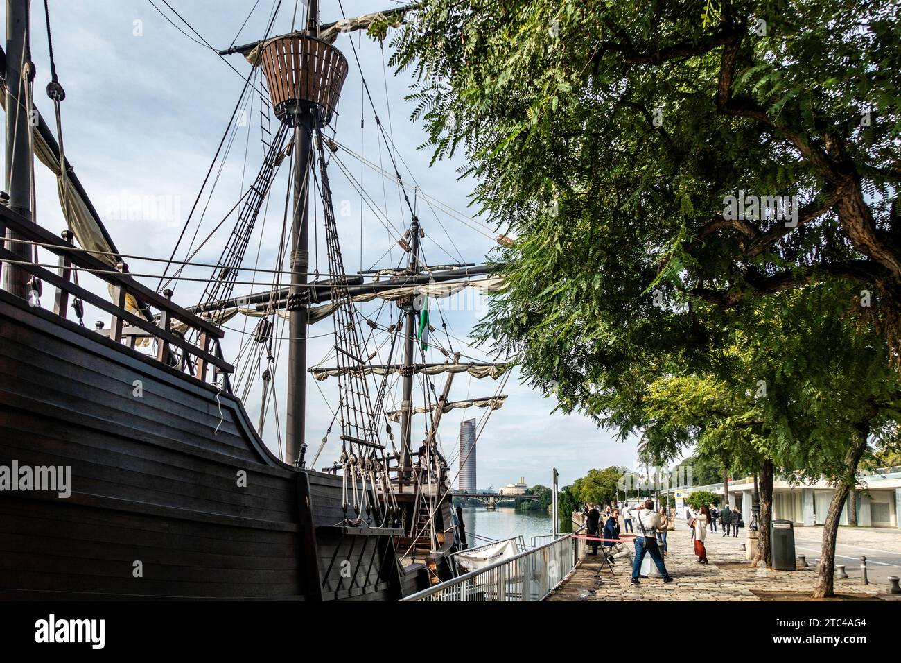 A detailed replica of a historic sailing ship moored along the serene Guadalquivir River, inviting exploration into Spain's maritime past. Stock Photo