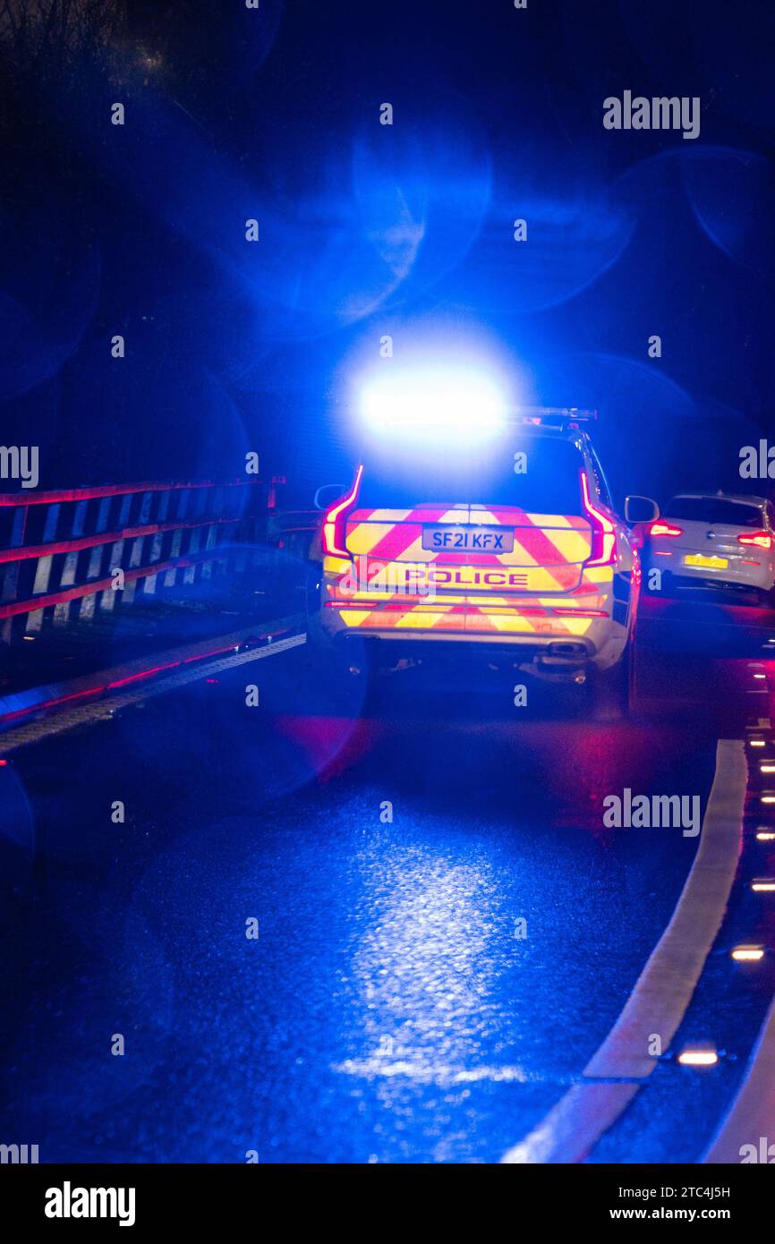 Police car with blue flashing lights responding to an emergency at night - Glasgow, Scotland, UK Stock Photo