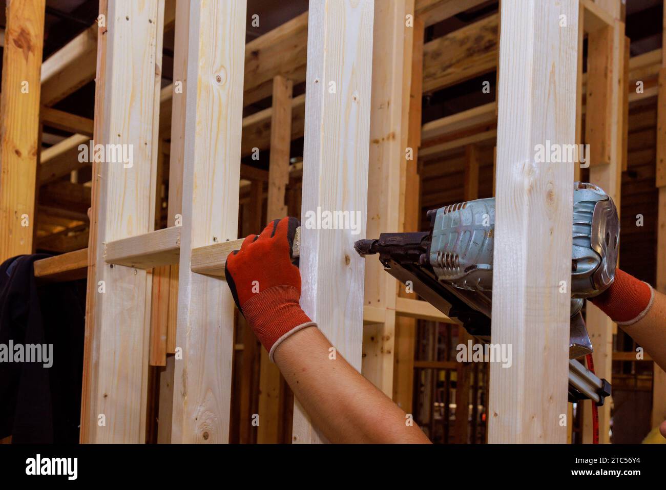 Builder nails wooden beams to house frameworks with use of an air