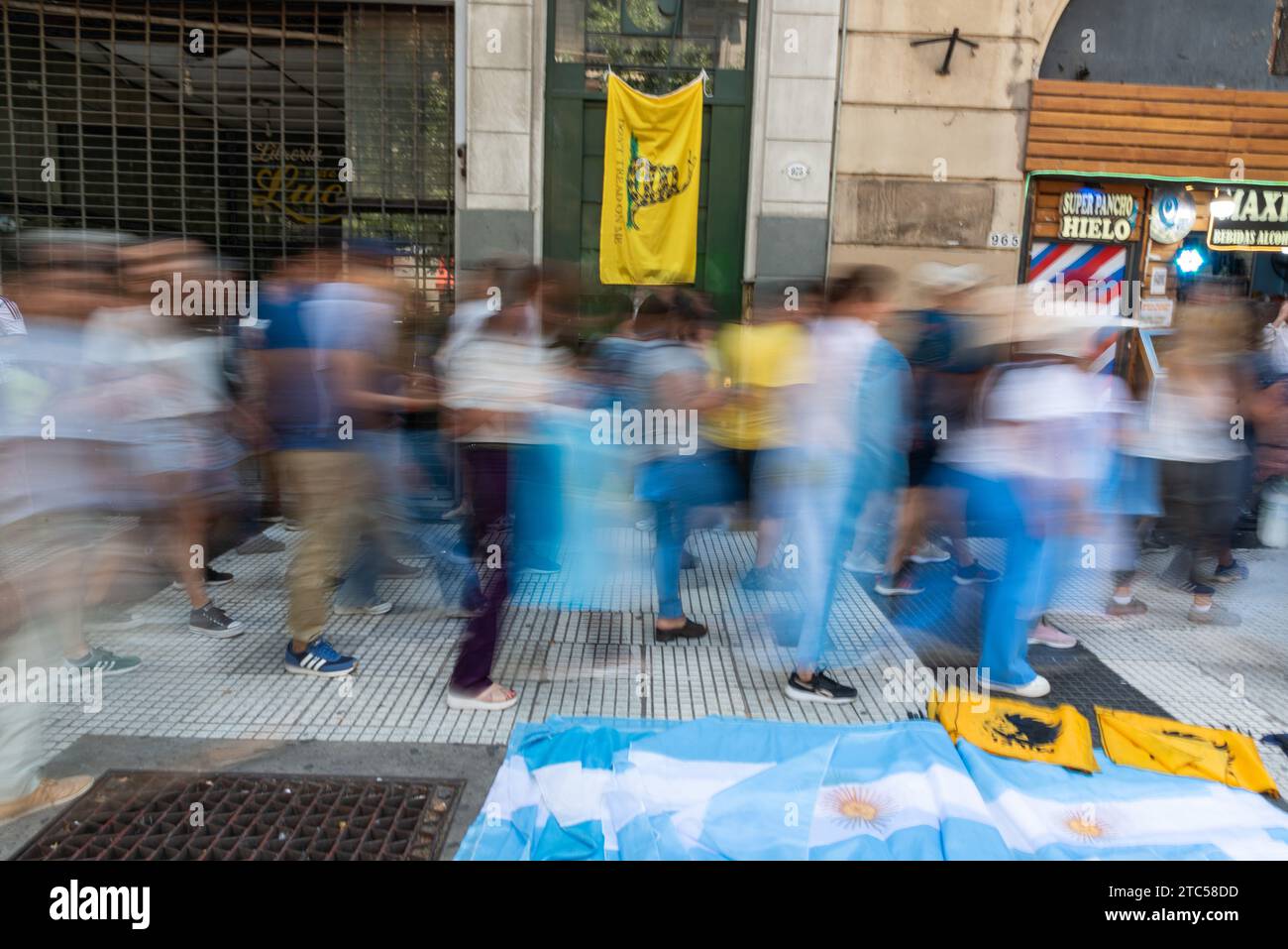 Buenos Aires, Argentina. 11th Feb, 2014. Dec 10, 2023 - Buenos Aires, Argentina - Milei supporters passing by in front of a Libertarian flag. Javier Milei was sworn in before the Legislative Assembly in the National Congress and assumed the presidency. After taking the oath, he spoke on the steps of Parliament and then traveled to Casa Rosada in an open car. After receiving the foreign delegations he went out to the historic balcony of the Government House where he addressed his followers. Credit: ZUMA Press, Inc./Alamy Live News Stock Photo