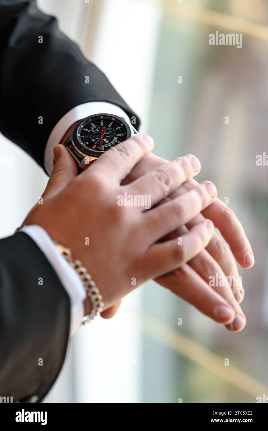 The morning of the groom on the wedding day before the wedding ceremony, the man adjusts the clock on his hand. Stock Photo